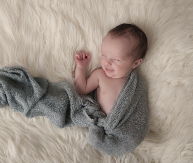 Peacefully sleeping newborn swaddled in soft gray
