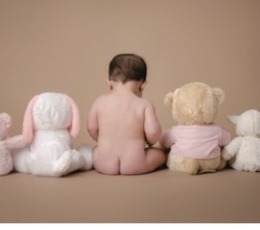 Baby seated between teddy bears